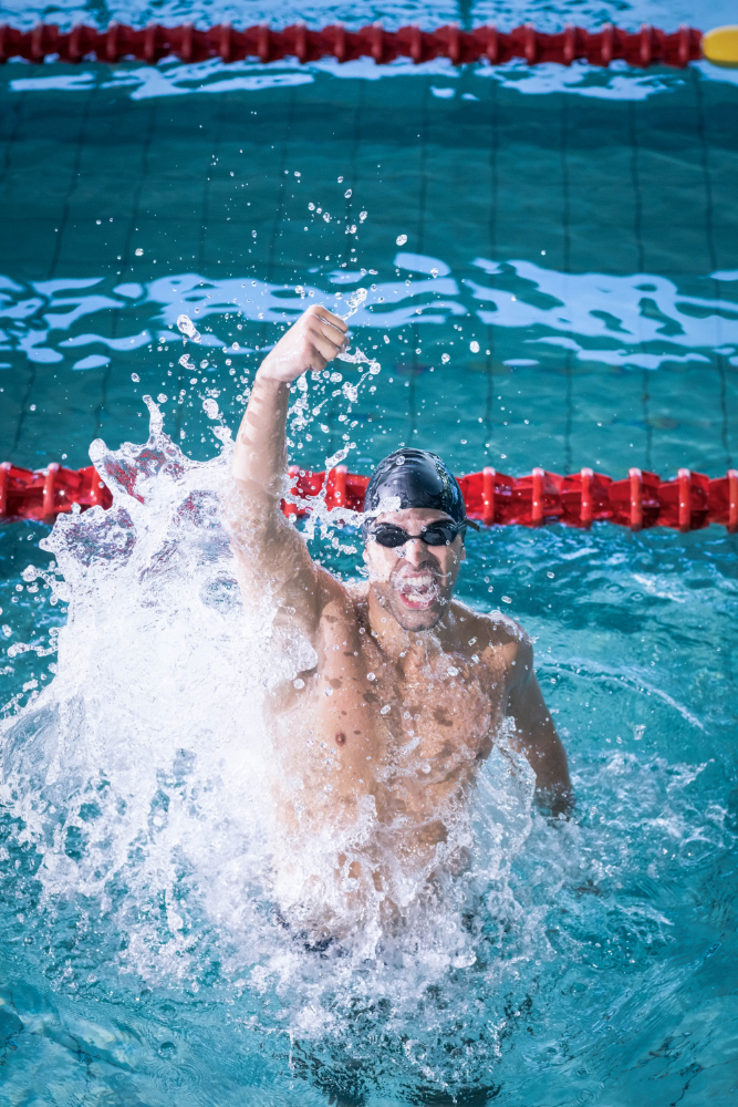 fit man triumphing with fist up pool